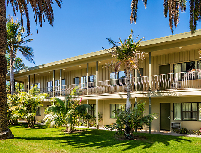 Exterior view of Courtside Garden View rooms with palm trees and grass at the Bahia Resort Hotel in Mission Beach, San Diego